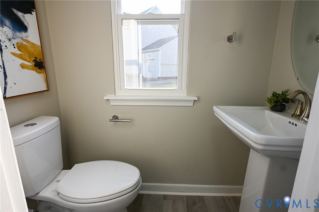 912 Harmony Road, Fairfield, VA 23059 Compact powder room featuring a ceramic pedestal sink with chrome faucet, a low-flow toilet with elongated bowl, and a large window providing natural light