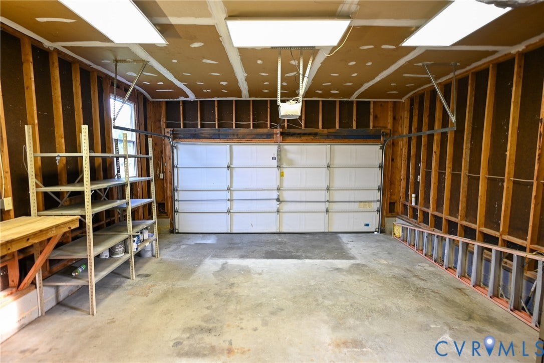 912 Harmony Road, Fairfield, VA 23059 Concrete flooring, an overhead garage door, exposed wood framing, and fluorescent ceiling lights