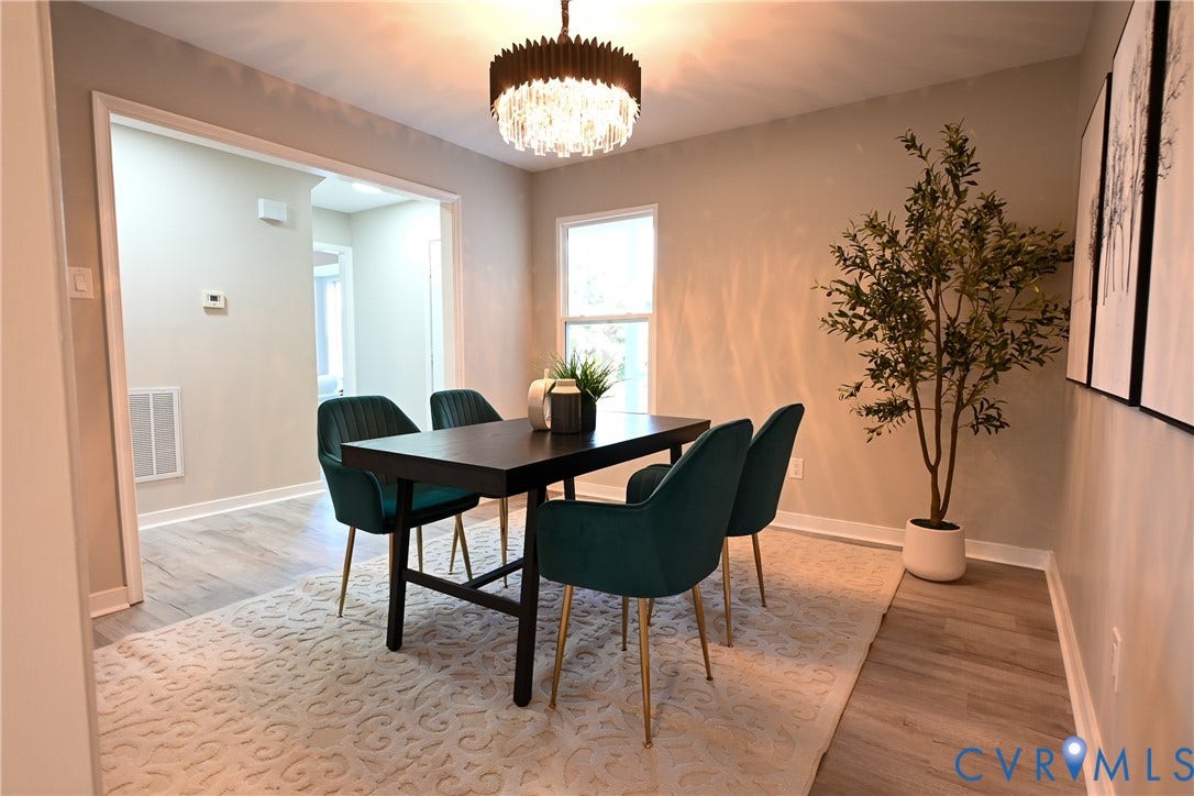 912 Harmony Road, Fairfield, VA 23059 Elegant dining space featuring a black wood table, contemporary upholstered chairs with metal legs, warm neutral wall finishes, and a statement pendant light fixture