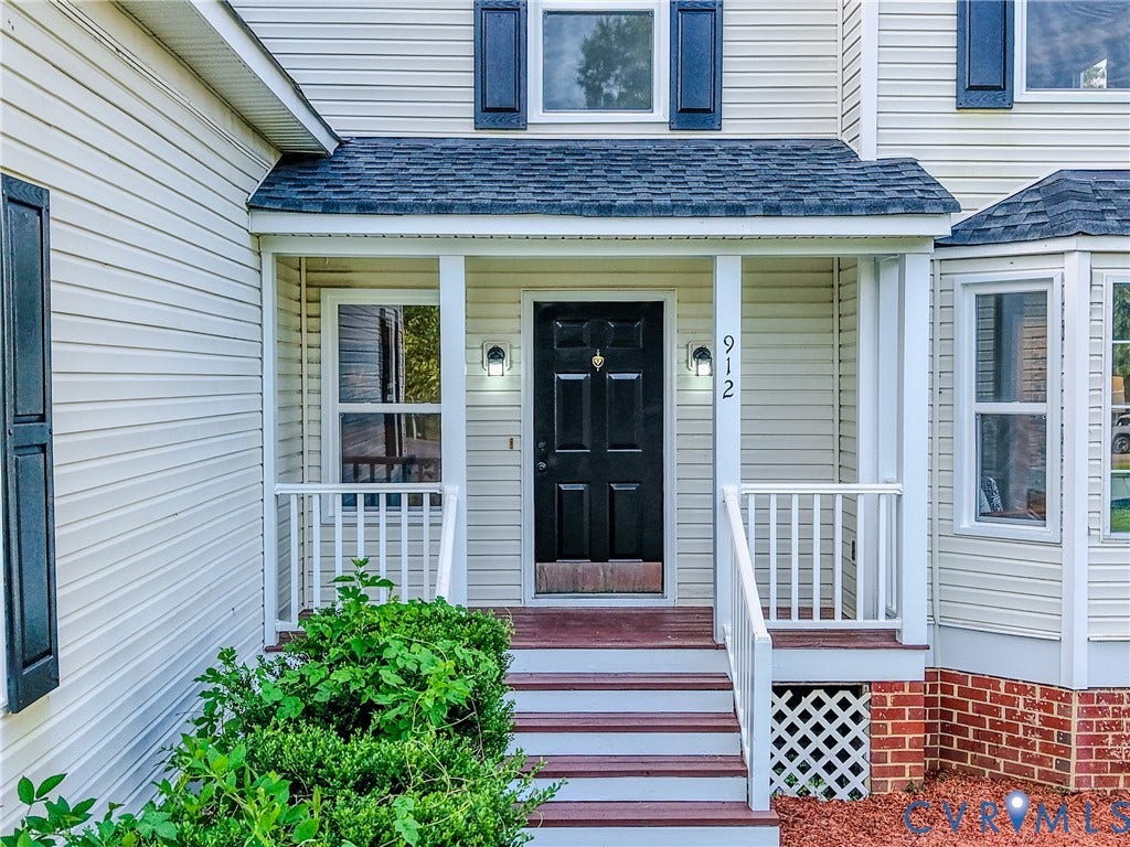 912 Harmony Road, Fairfield, VA 23059 Covered front entry with a dark panel door, white railings, and exterior wall sconces