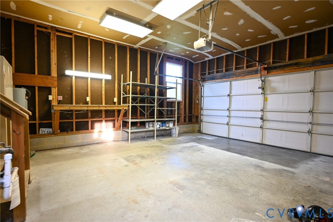 912 Harmony Road, Fairfield, VA 23059 Spacious garage featuring two overhead doors with panels, polished concrete flooring, wood-framed structural supports, recessed ceiling lighting, and a side entry door providing convenient access