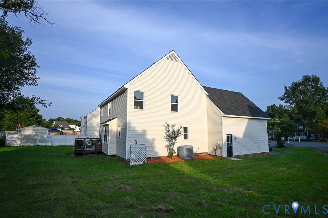912 Harmony Road, Fairfield, VA 23059 White vinyl siding exterior with a dark shingle roof, featuring a wooden deck, multiple windows, and a side entry door