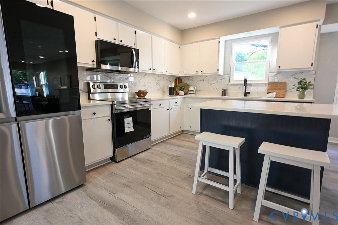 912 Harmony Road, Fairfield, VA 23059 Kitchen featuring white shaker cabinetry, stainless steel appliances, marble-look backsplash, light wood-finish flooring, and a center island with a light-toned countertop