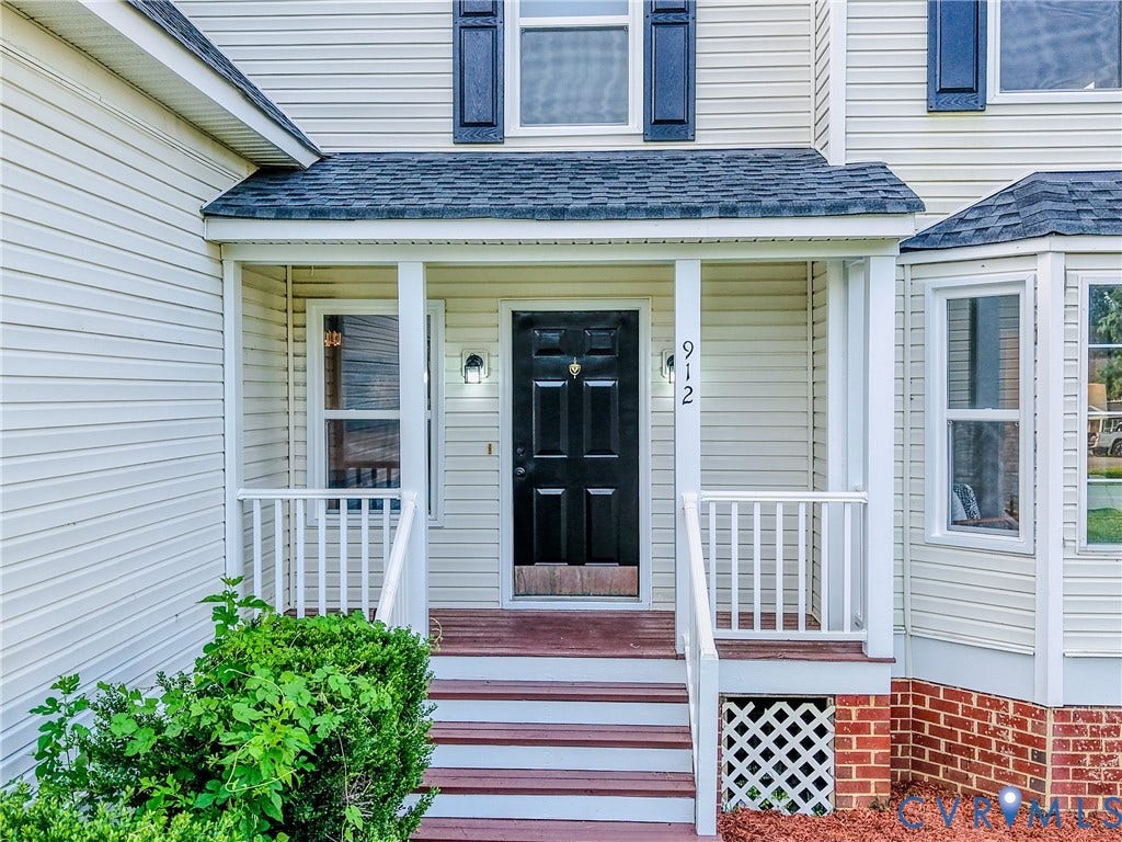 912 Harmony Road, Fairfield, VA 23059 Covered entry porch featuring white columns and railings, wood-finish steps, and a dark paneled door
