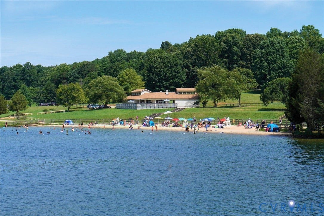 126 Reedy Creek Road, Reedy Creek, Louisa, VA 23093 Expansive lakefront setting featuring a sandy beach, clear blue water, and a backdrop of lush green trees