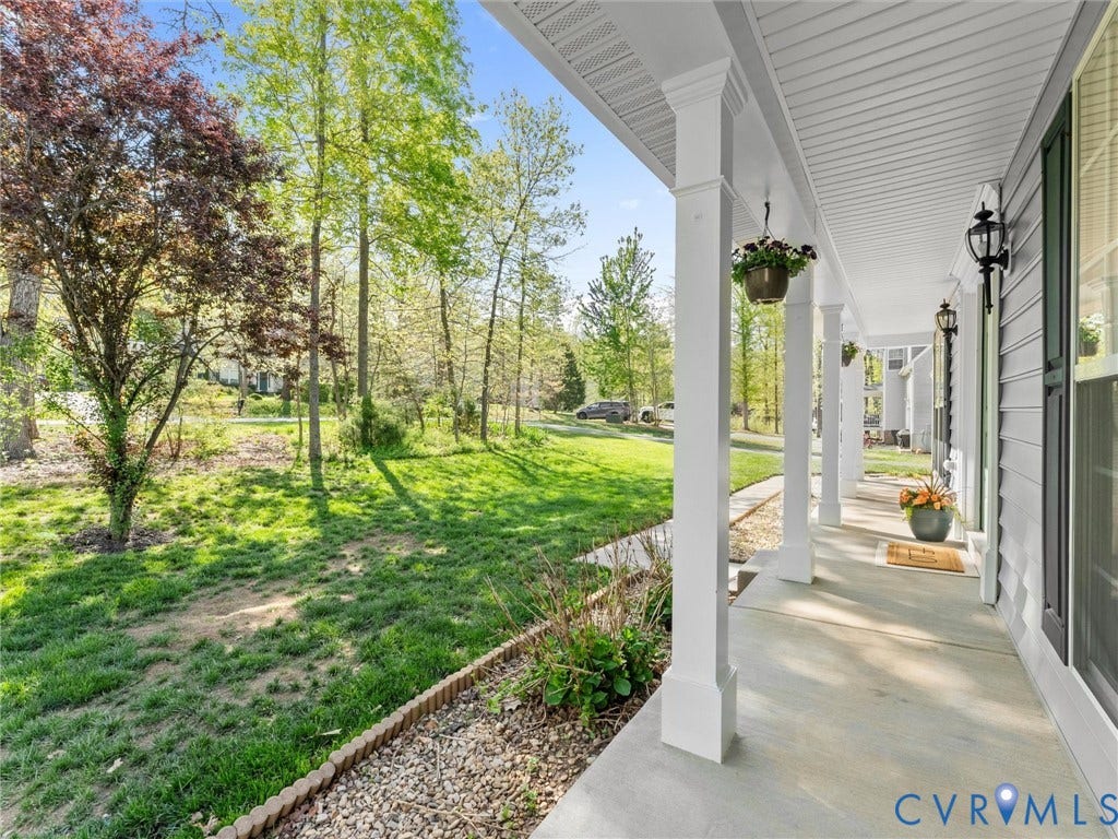 126 Reedy Creek Road, Reedy Creek, Louisa, VA 23093 The property features a charming covered porch with white columns and exterior lighting, overlooking a verdant lawn with mature trees