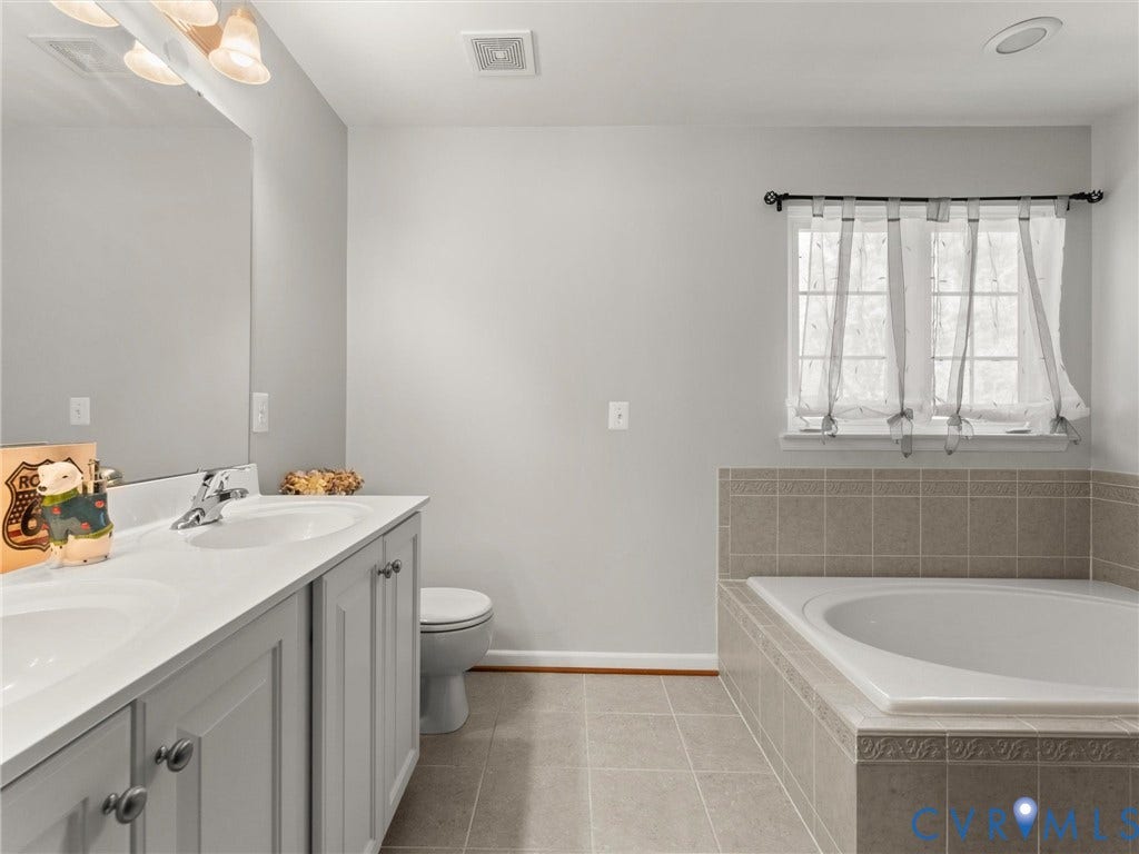 126 Reedy Creek Road, Reedy Creek, Louisa, VA 23093 Bathroom featuring a double vanity with light gray cabinetry, a built-in bathtub with tiled surround, and a window providing natural light