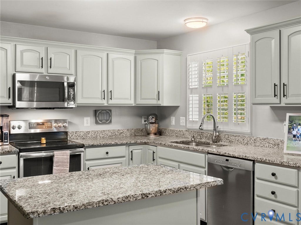 126 Reedy Creek Road, Reedy Creek, Louisa, VA 23093 The kitchen features white cabinetry with black hardware, granite countertops, and stainless steel appliances including a microwave, range, and dishwasher
