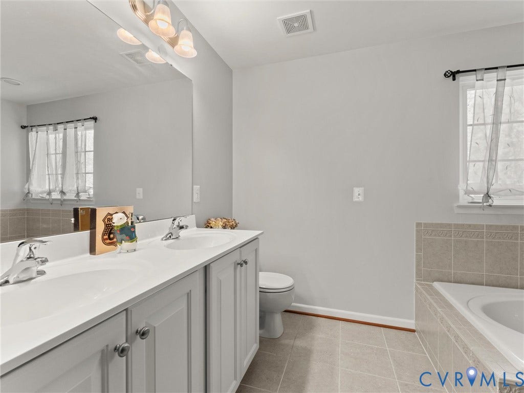 126 Reedy Creek Road, Reedy Creek, Louisa, VA 23093 Bathroom featuring a dual vanity with light-colored cabinets and a large mirror, a toilet, and a tiled built-in tub