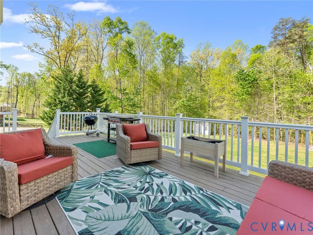 126 Reedy Creek Road, Reedy Creek, Louisa, VA 23093 The property features an outdoor deck with a white railing, overlooking a lush green landscape with trees and grass