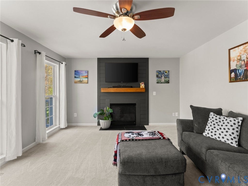 126 Reedy Creek Road, Reedy Creek, Louisa, VA 23093 Living room featuring light-colored carpeting, a ceiling fan with integrated lighting, and a fireplace with a dark-colored surround and a wooden mantel