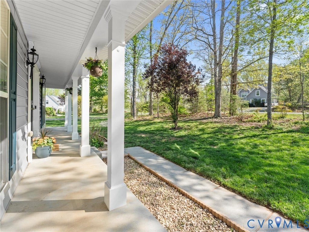 126 Reedy Creek Road, Reedy Creek, Louisa, VA 23093 The property features a charming front porch with white pillars, a concrete walkway, and a well-maintained lawn bordered by mature trees