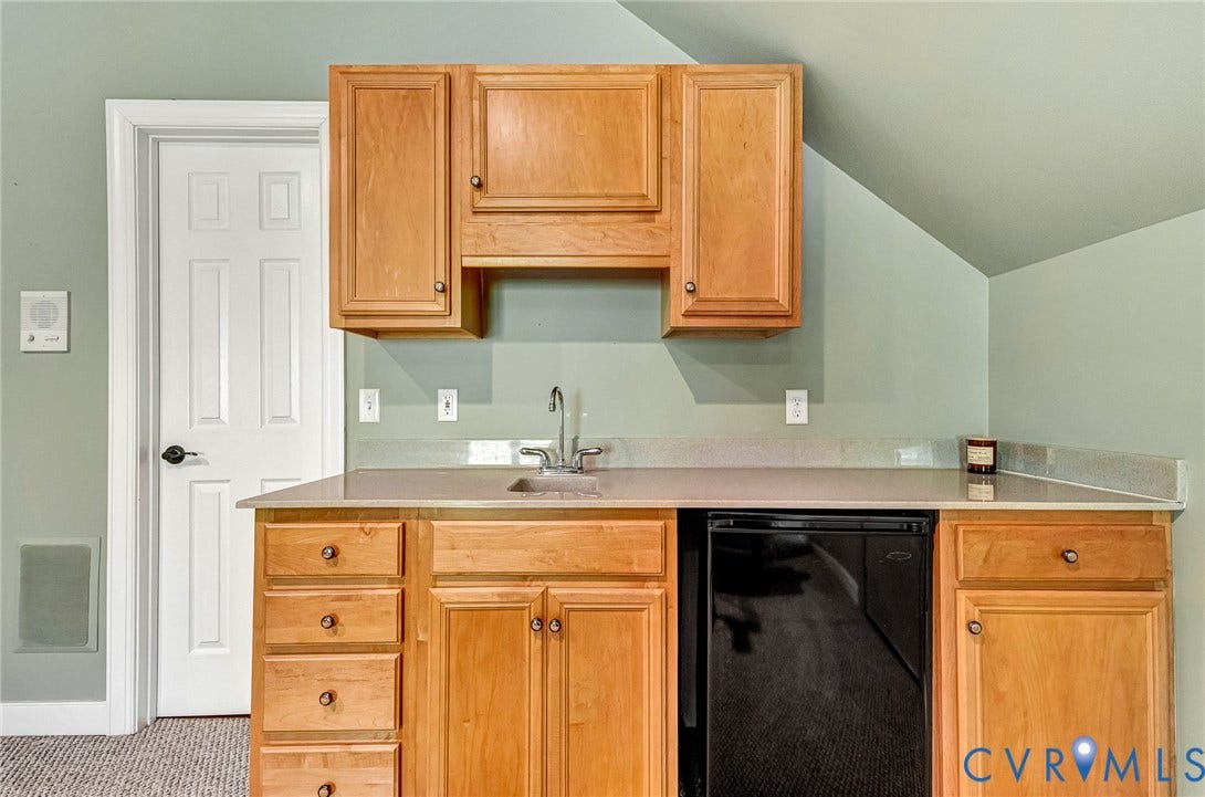 3131 Shadow Creek Drive, Powhatan, VA 23139 Built-in wet bar featuring a stainless steel sink, light wood cabinetry, stone countertop, and an under-counter beverage refrigerator