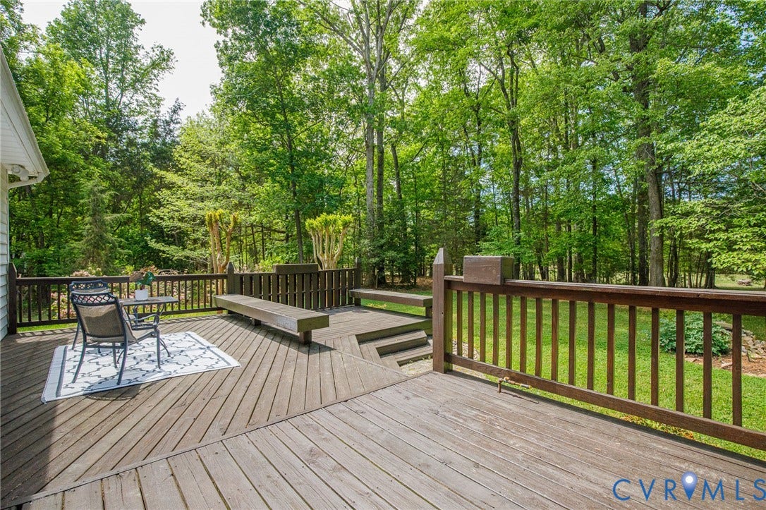 3131 Shadow Creek Drive, Powhatan, VA 23139 Multi-level wood deck featuring built-in benches, dark wood railings, and a verdant tree-lined perimeter
