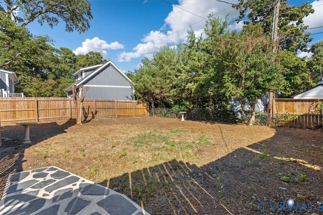 613 Maple Avenue, Near West End, Richmond, VA 23226 Expansive backyard with a wood privacy fence, mature trees, and a stone patio