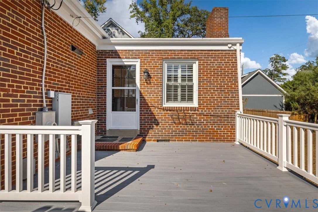 613 Maple Avenue, Near West End, Richmond, VA 23226 Brick exterior with white trim, wood-finish decking, white railing, and a brick chimney