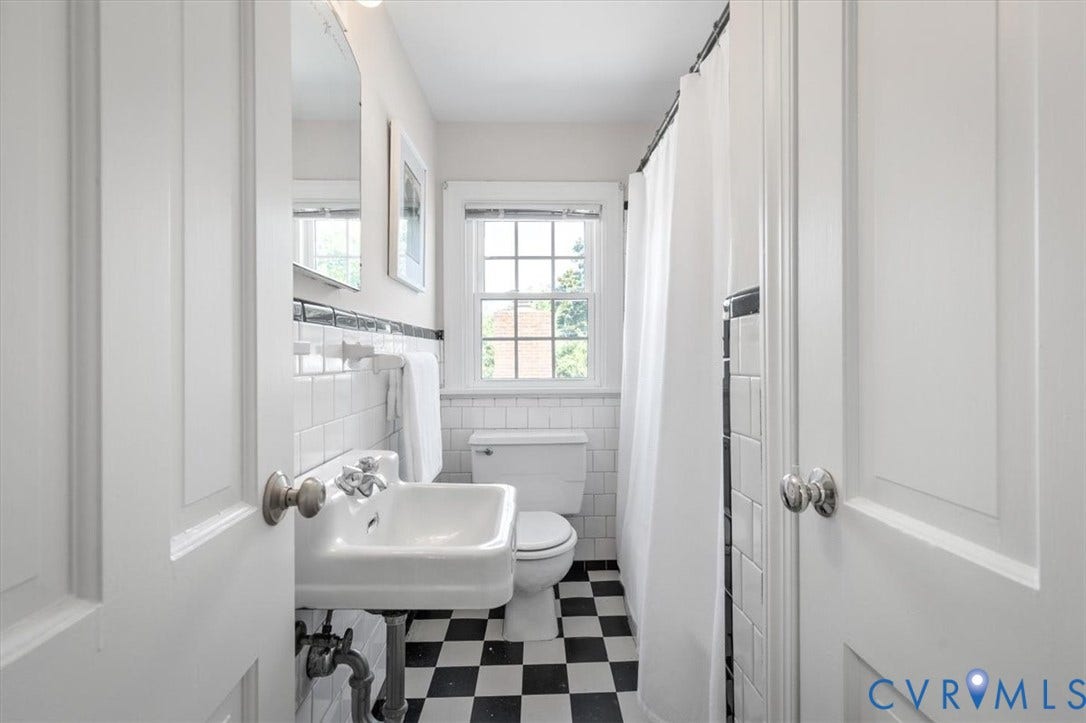 613 Maple Avenue, Near West End, Richmond, VA 23226 Pedestal sink, black and white checkered floor tiling, white subway tile wall surround, double-hung window, and a shower with a white curtain
