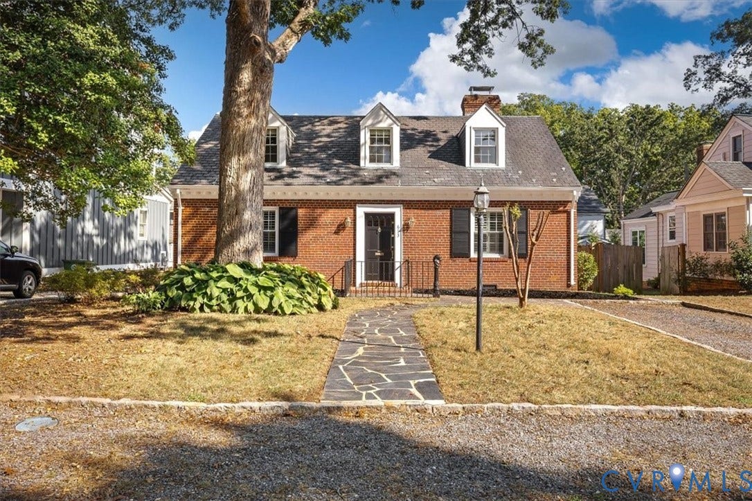 613 Maple Avenue, Near West End, Richmond, VA 23226 Brick exterior with black shutters and white trim, featuring a dark shingle roof and three dormer windows
