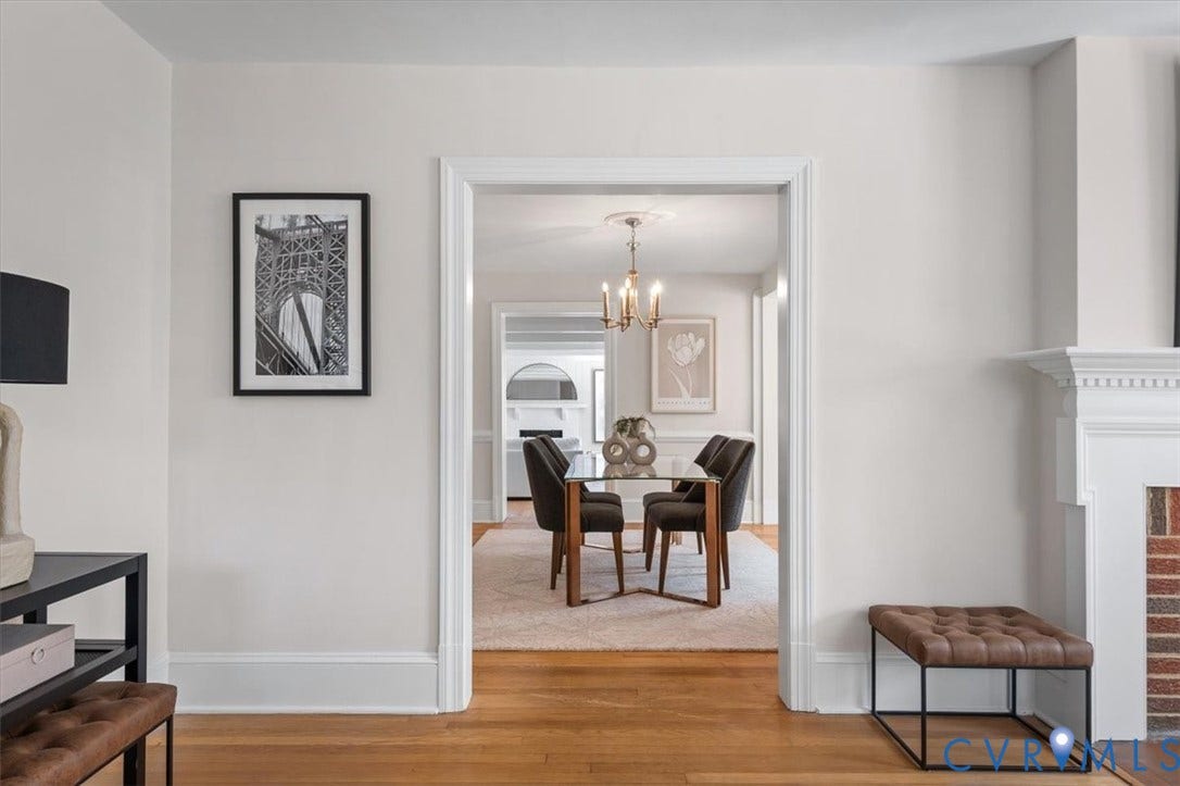 613 Maple Avenue, Near West End, Richmond, VA 23226 Hardwood flooring, cased entryway, white trim, brick fireplace surround, and decorative chandelier