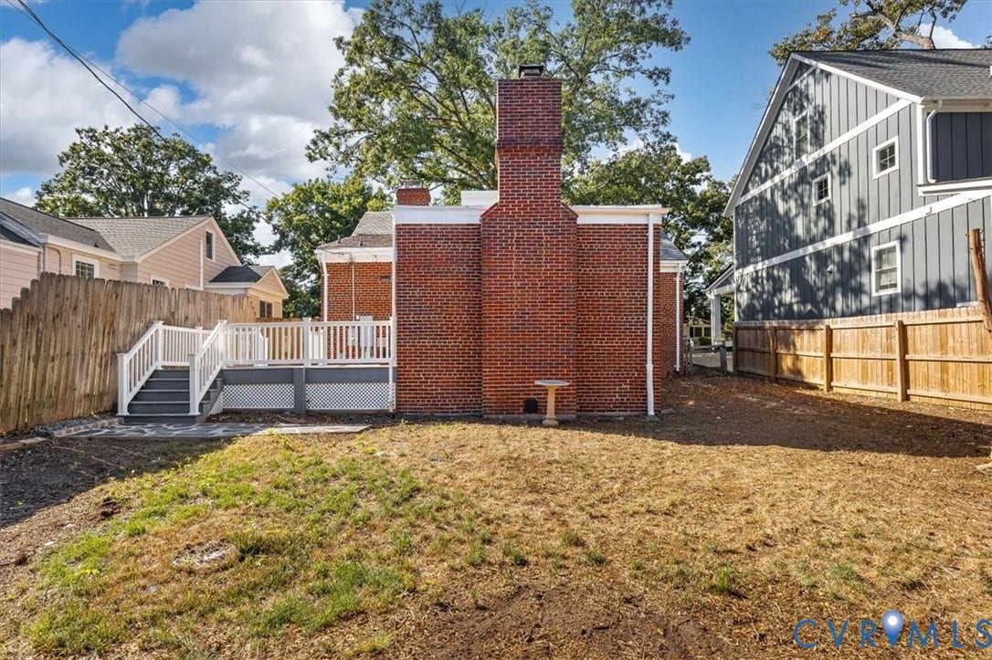 613 Maple Avenue, Near West End, Richmond, VA 23226 Brick exterior with prominent chimney, raised deck featuring white railings and steps, and wood fencing