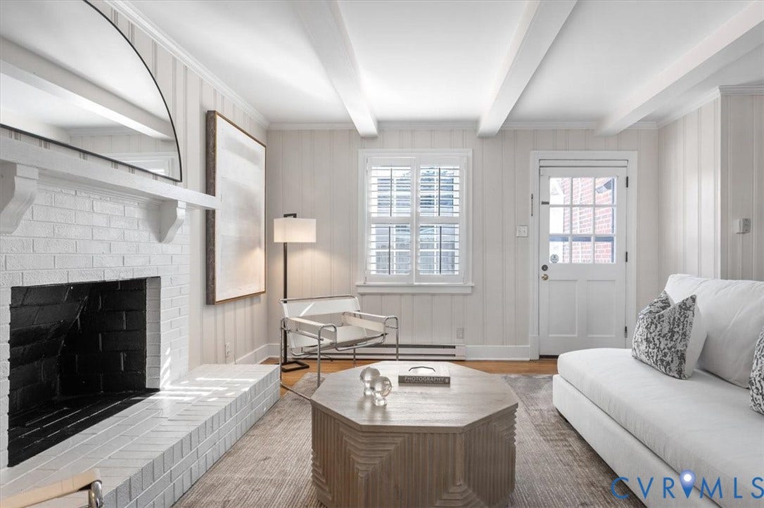 613 Maple Avenue, Near West End, Richmond, VA 23226 Exposed ceiling beams, white brick fireplace with hearth, wood-finish flooring, paneled walls, and a glass-paneled door