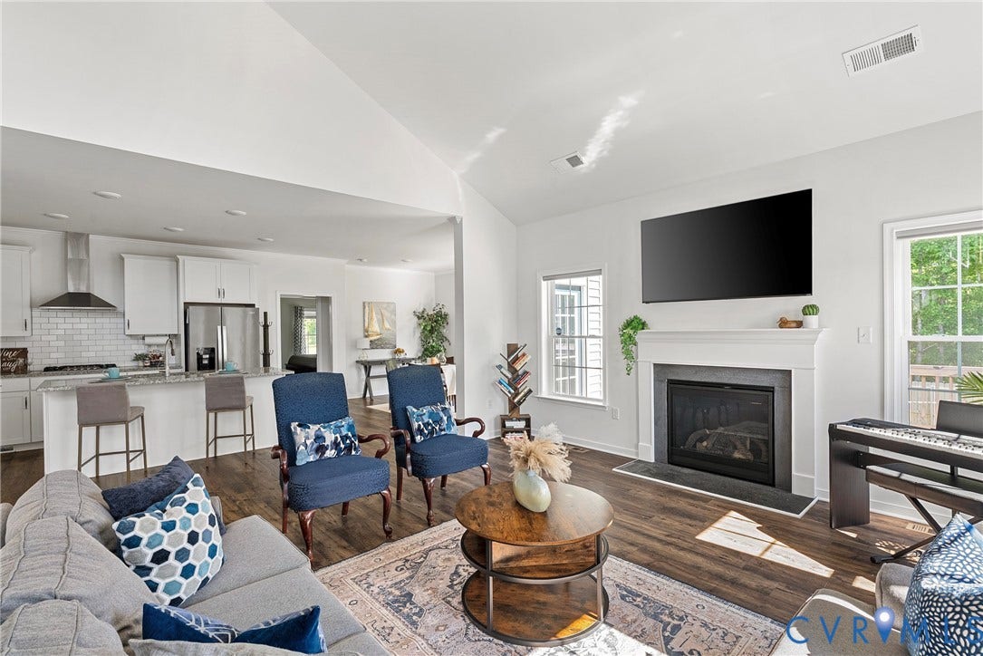 1605 Reed Marsh Place, Reed Marsh, Goodview, VA 23063 Spacious living room featuring vaulted ceilings, wood-finish flooring, a fireplace with a white mantel, and multiple large windows delivering loads of light.