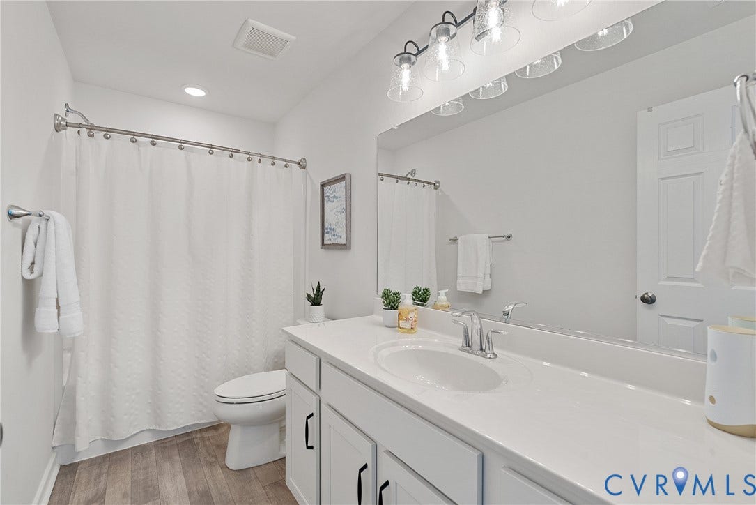 1605 Reed Marsh Place, Reed Marsh, Goodview, VA 23063 Full 2nd floor bathroom featuring a single vanity with an integrated sink, white cabinetry with black hardware, and a large wall-mounted mirror. Full shower/tub.