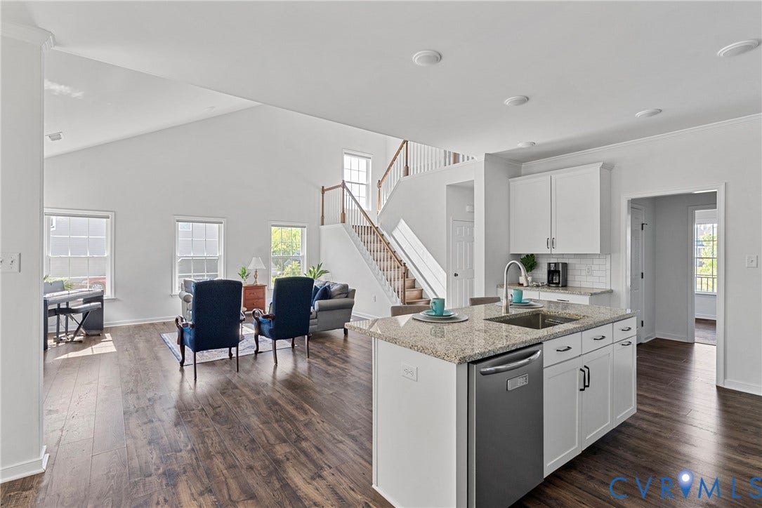1605 Reed Marsh Place, Reed Marsh, Goodview, VA 23063 Open-concept living space featuring wood-finish flooring, a kitchen island with granite countertops and an undermount sink, white cabinetry, and a subway tile backsplash