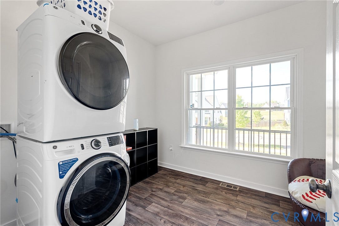 1605 Reed Marsh Place, Reed Marsh, Goodview, VA 23063 1st floor laundry room featuring a full-size stacked washer and dryer, wood-finish flooring, and a large window with grid panes