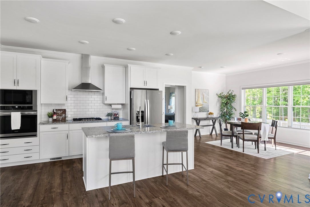 1605 Reed Marsh Place, Reed Marsh, Goodview, VA 23063 Open-concept kitchen and dining area featuring wood-finish flooring, white cabinetry, a central island with a granite countertop, and stainless steel appliances.
