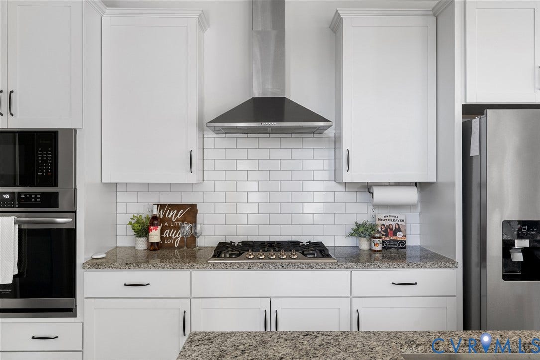 1605 Reed Marsh Place, Reed Marsh, Goodview, VA 23063 Kitchen showcasing white shaker-style cabinetry, a built-in stainless steel microwave and oven, a gas cooktop, a stainless steel range hood, and subway tile backsplash.