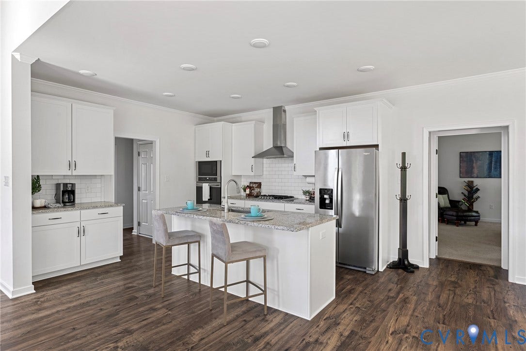 1605 Reed Marsh Place, Reed Marsh, Goodview, VA 23063 Spacious kitchen featuring an island with counter seating, granite countertops, white cabinetry, stainless steel appliances, and wood-finish flooring