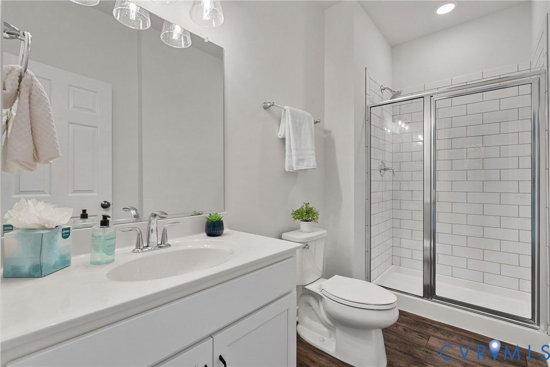 1605 Reed Marsh Place, Reed Marsh, Goodview, VA 23063 1st floor full bathroom featuring a subway tile shower with glass enclosure, white vanity with integrated sink, chrome faucet, and wood-finish flooring