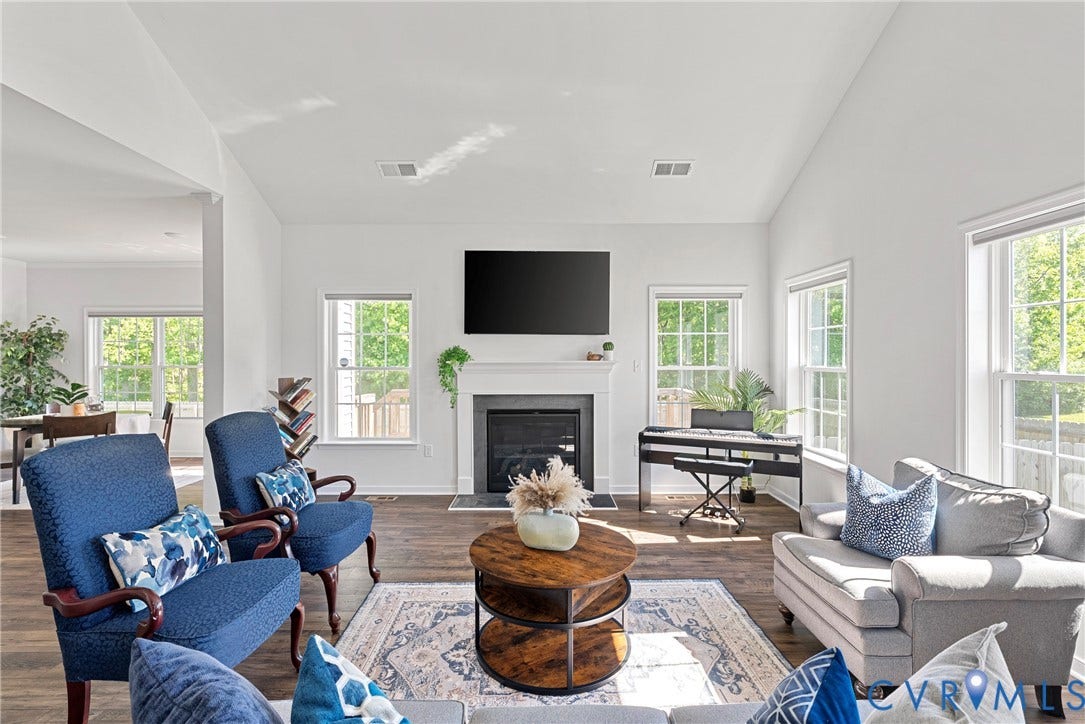 1605 Reed Marsh Place, Reed Marsh, Goodview, VA 23063 Spacious living room featuring vaulted ceilings, wood-finish flooring, a fireplace with a white mantel, and multiple large windows delivering loads of light.