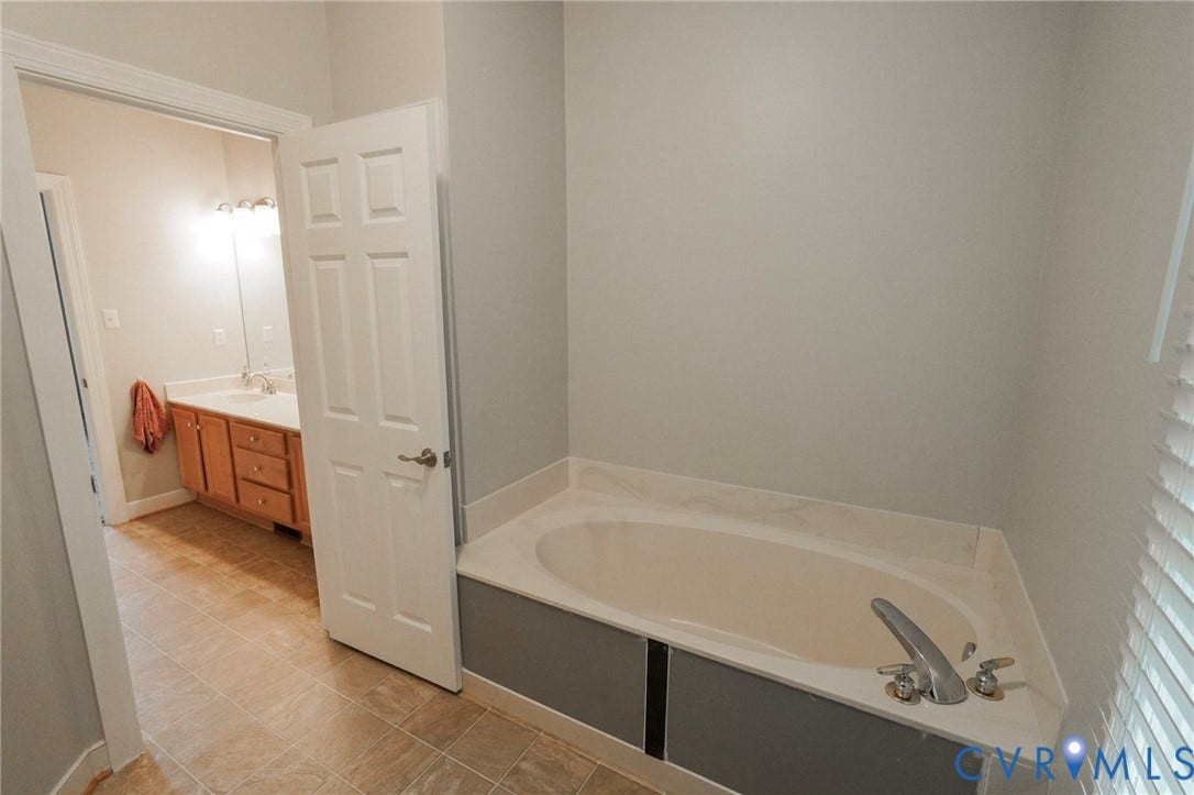 1670 Mill Quarter Road, Powhatan, VA 23139 Primary Bathroom featuring a soaking tub with dual faucet, neutral tile flooring, and soft neutral wall finishes