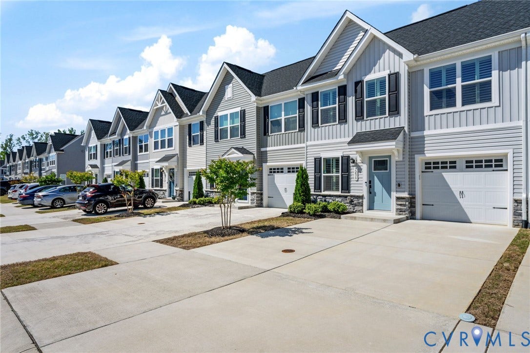 7236 George Wythe Lane, Summer Maple, New Kent, VA 23124 Contemporary townhome exterior featuring light gray siding with dark shutters, individual garages, a pale blue entry door, and a covered porch entry