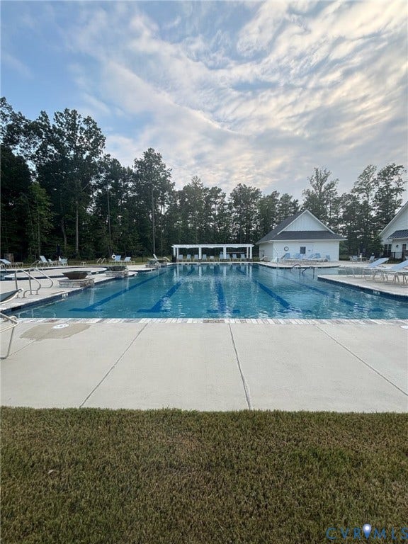 7236 George Wythe Lane, Summer Maple, New Kent, VA 23124 Outdoor swimming pool featuring lap lanes, surrounding concrete decking, and a white pergola structure