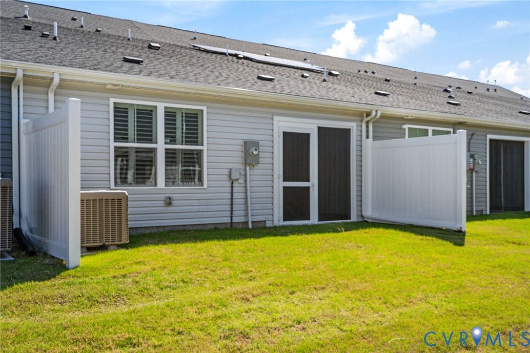 7236 George Wythe Lane, Summer Maple, New Kent, VA 23124 Exterior rear featuring a manicured lawn, vinyl siding, white vinyl privacy fence, and sliding glass door with screen