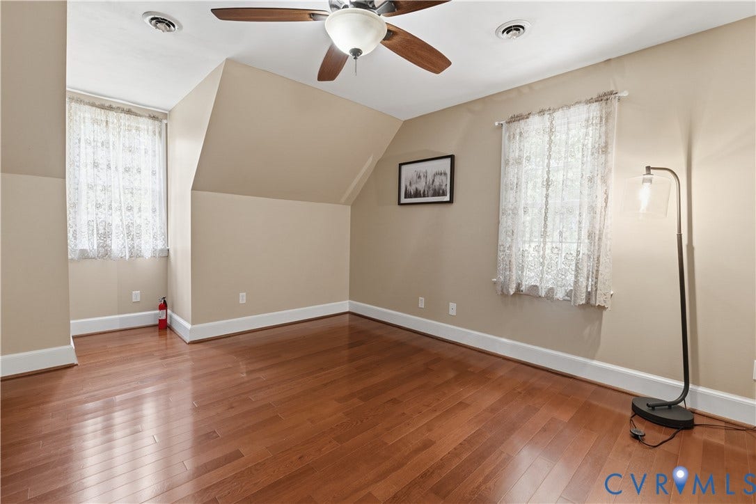 9803 Gates Bluff Drive, Gates Bluff, Chesterfield, VA 23832 Spacious room featuring wood-finish flooring, two windows, and a ceiling fan with integrated lighting