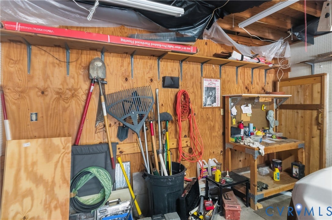 9803 Gates Bluff Drive, Gates Bluff, Chesterfield, VA 23832 Garage featuring plywood wall paneling, built-in shelving, a dedicated workbench, fluorescent lighting, and a partially visible vehicle