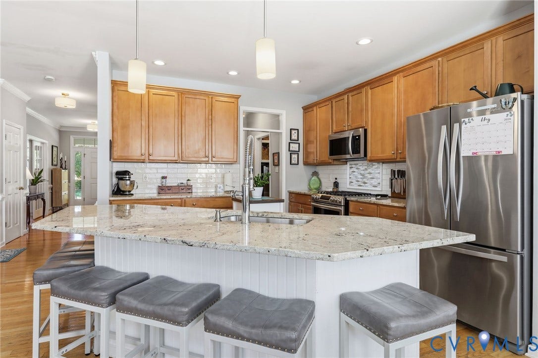 4909 Parsons Walk Place, Twin Hickory, Glen Allen, VA 23059 Kitchen featuring light wood cabinetry, stainless steel appliances, a white subway tile backsplash, and a large central island with a light-toned countertop and paneled base