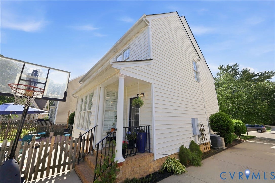 4909 Parsons Walk Place, Twin Hickory, Glen Allen, VA 23059 White siding exterior featuring a covered porch with white columns, black metal railings, a brick foundation, and a side-facing window on the upper level