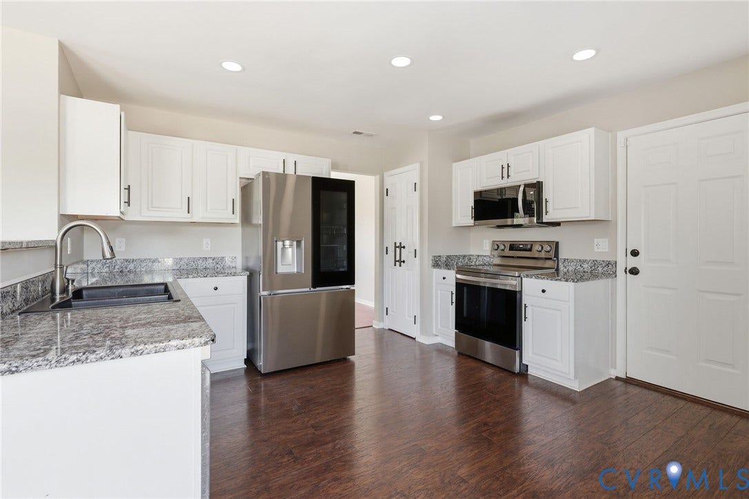Kitchen featuring wood-finish flooring, white cabinetry with dark hardware, stone countertops, stainless steel appliances, and recessed lighting