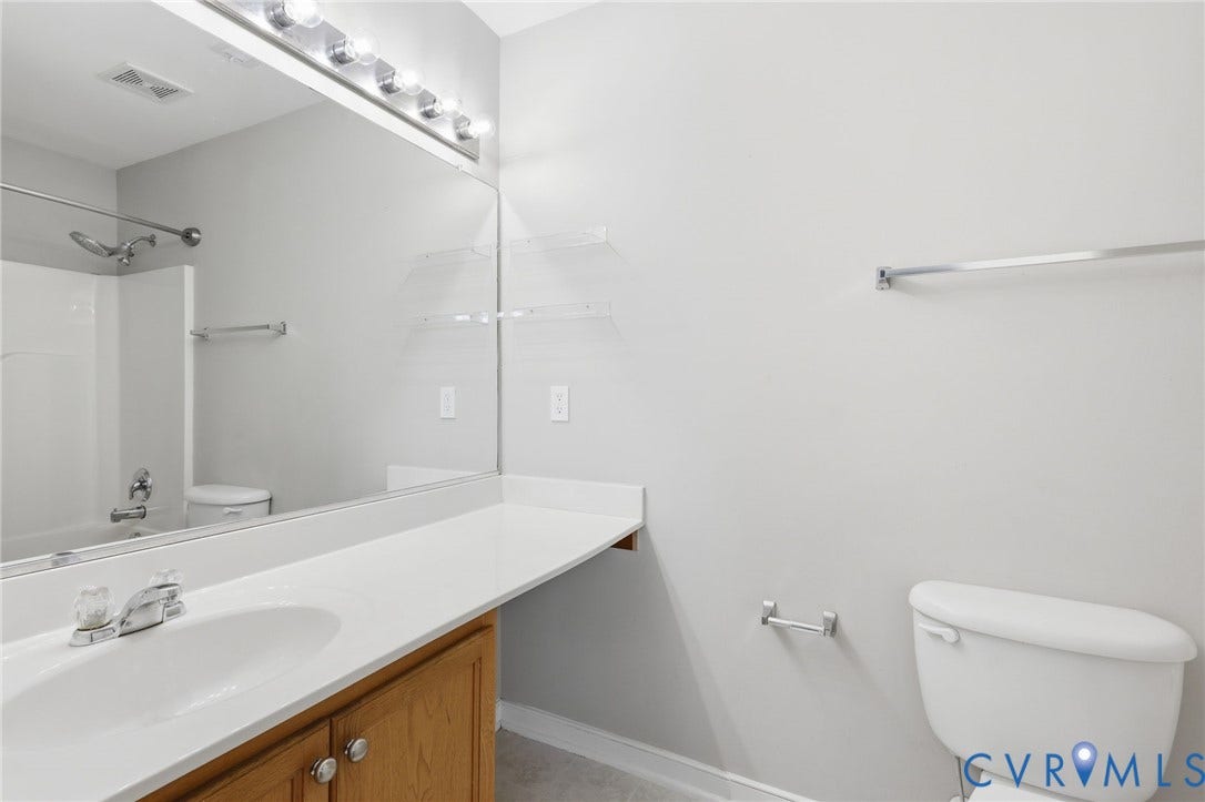Full bathroom featuring a single vanity with wood cabinetry, a white countertop, and an integrated sink
