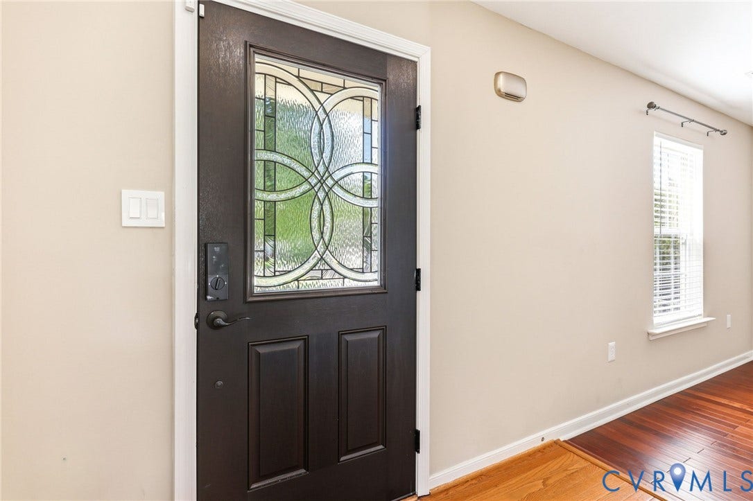 Entry door featuring decorative glass, paneling, and dark hardware