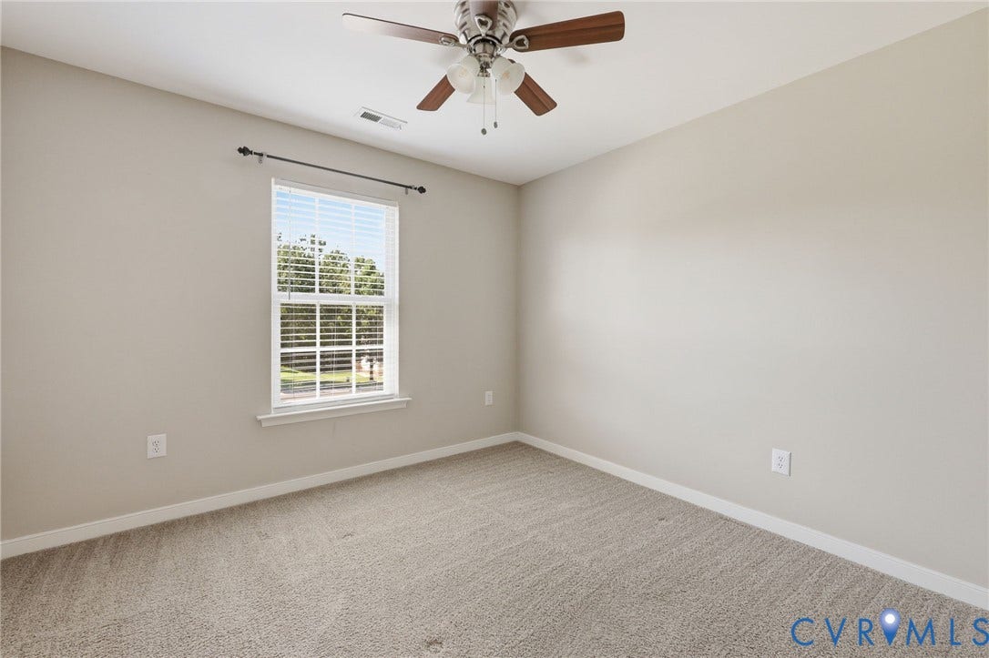 Carpeted room featuring a ceiling fan with light fixture, a window with blinds, and neutral painted walls