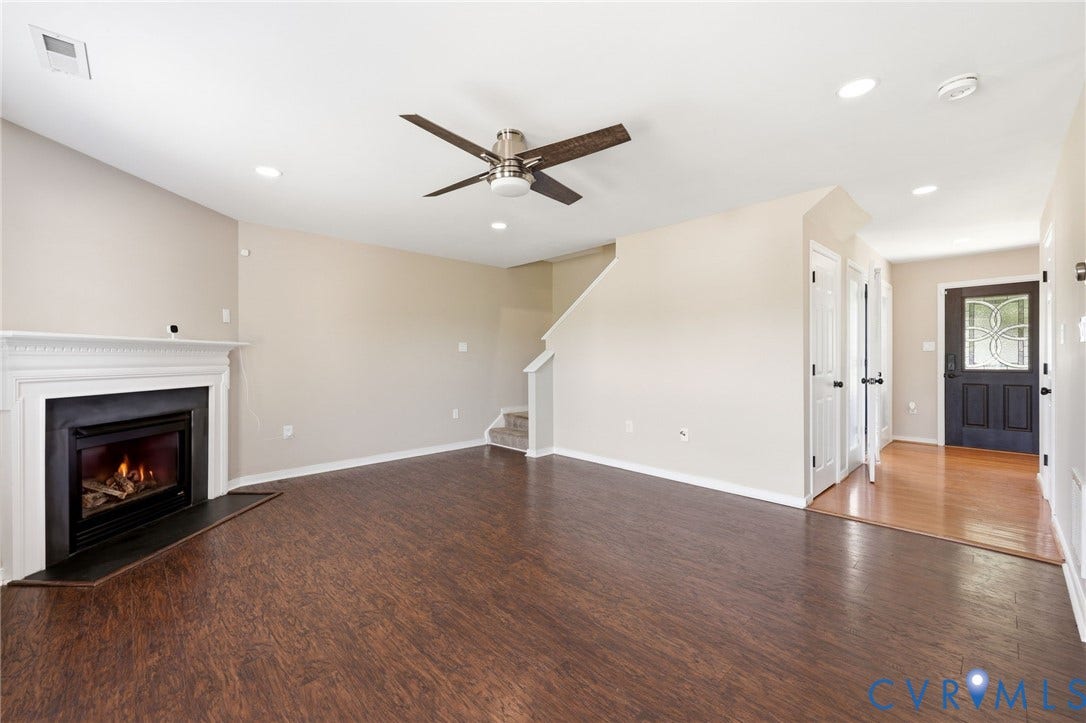 Spacious interior featuring wood-finish flooring, a white mantel fireplace, recessed lighting, and a ceiling fan
