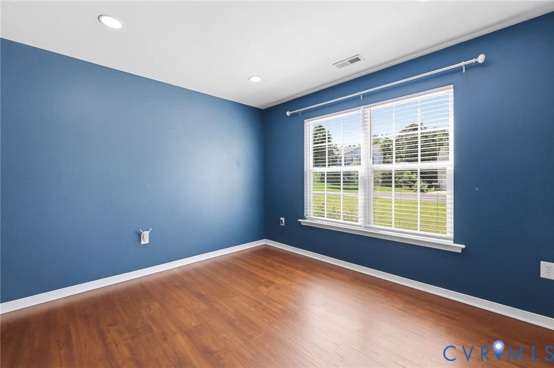 Room featuring blue painted walls, wood-finish flooring, and white trim