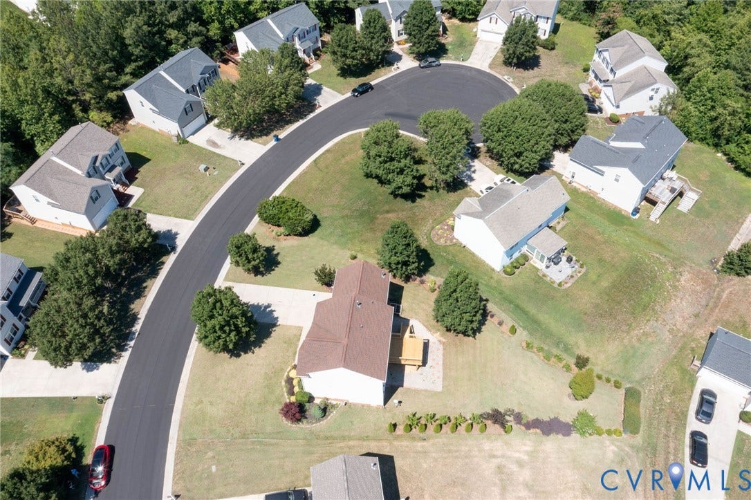 Aerial perspective of a residential cul-de-sac featuring multiple properties with varied rooflines and landscaped yards