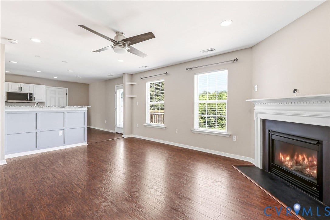 Spacious living area featuring wood-finish flooring, a white mantel fireplace, and recessed lighting